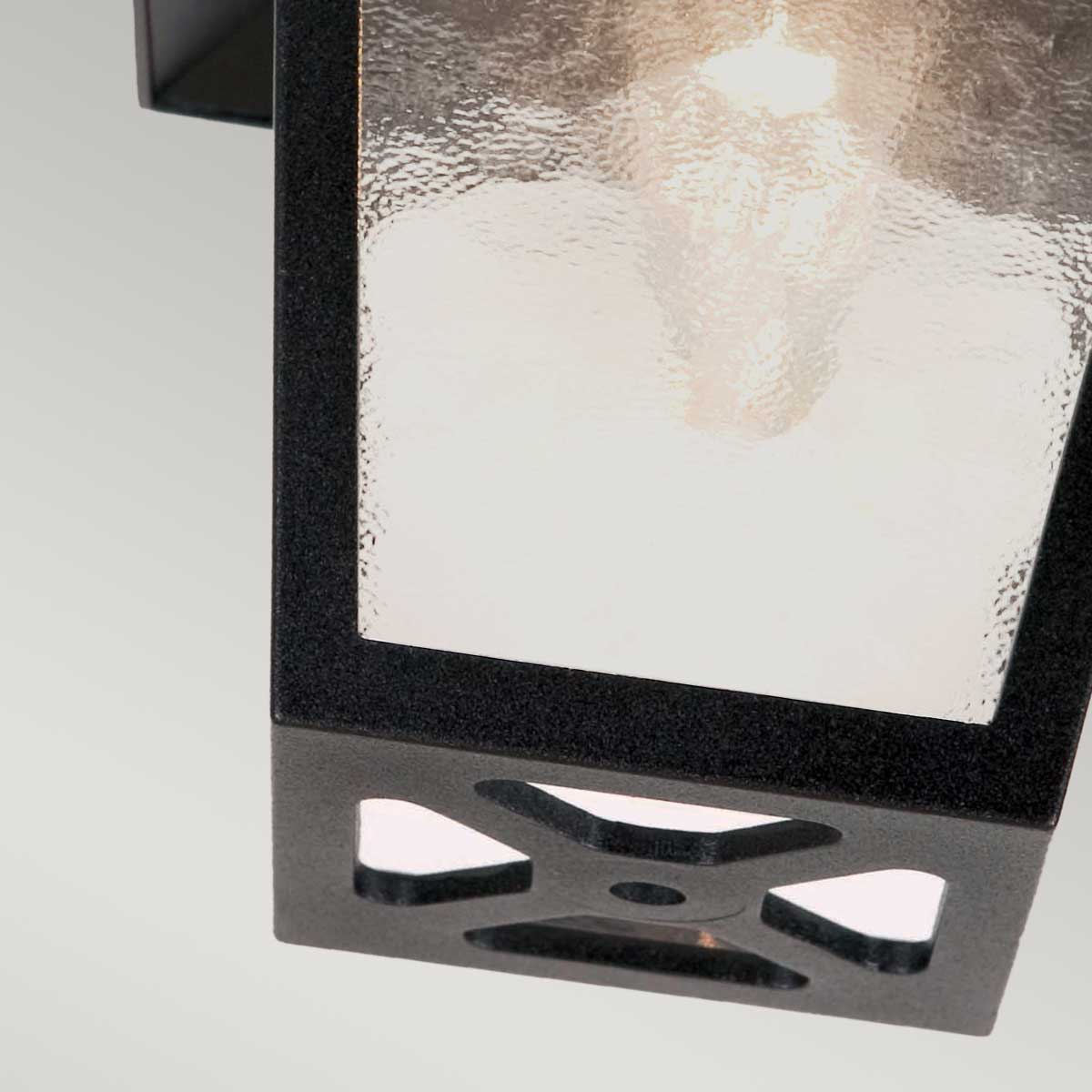 Bas du luminaire montrant découpes en croix et vis de fixation noire.