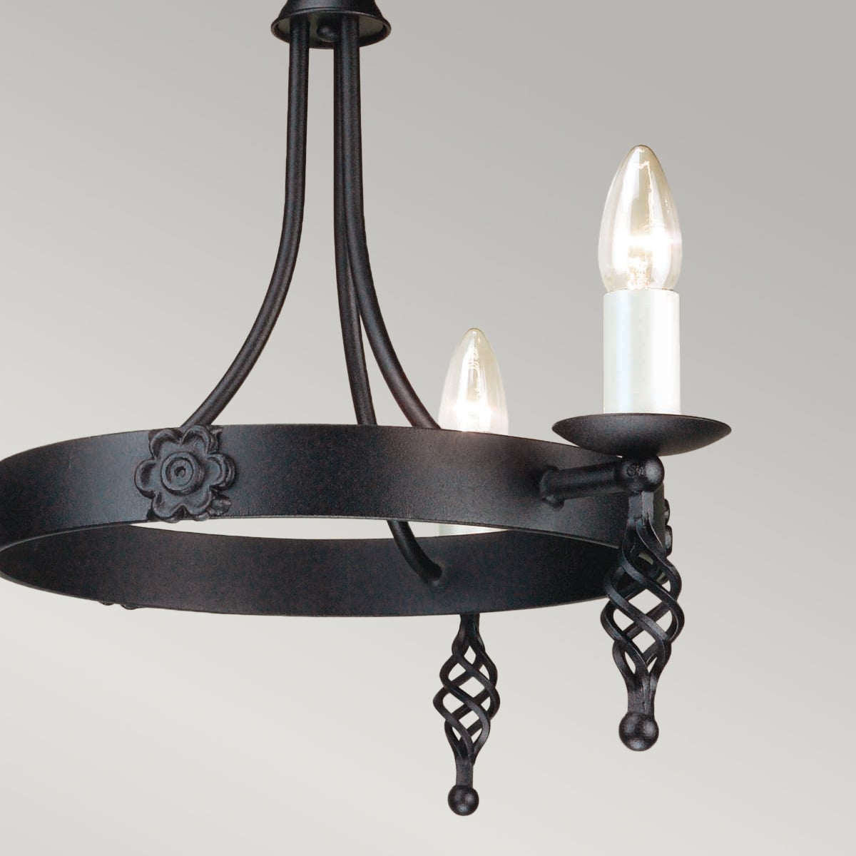 Vue rapprochée des bras, coupelles et bougies allumées du lustre.