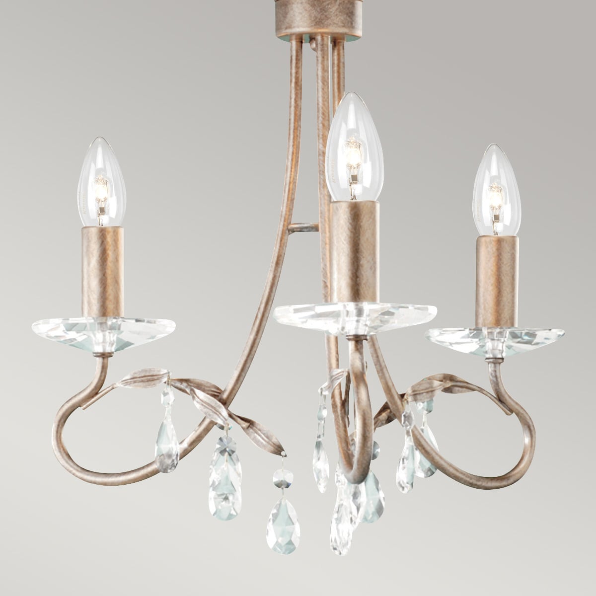 Gros plan sur les bras, coupelles et pampilles en cristal du luminaire.