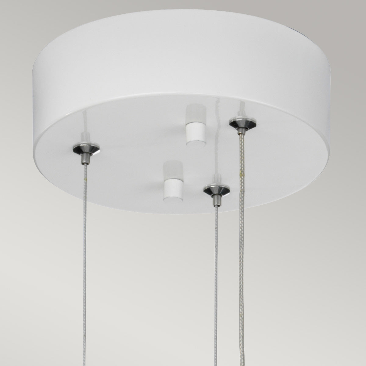 Détail de la rosace ronde blanche fixée au plafond, avec câbles et attaches