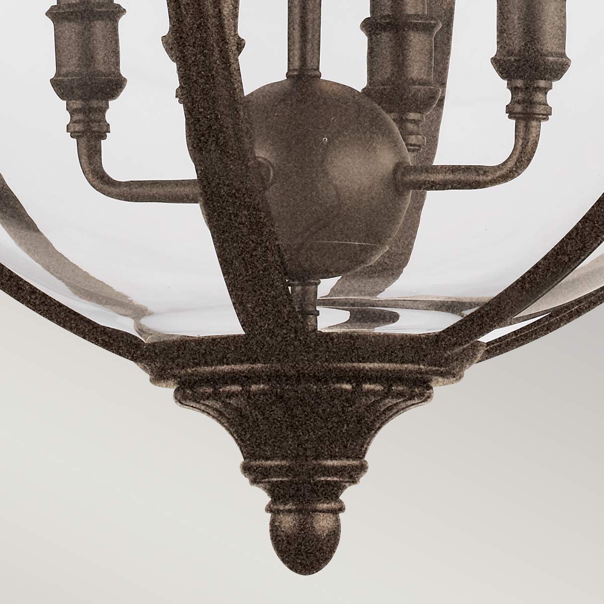 Détail du bas du luminaire : rosace godronnée et sphère centrale en métal patiné.