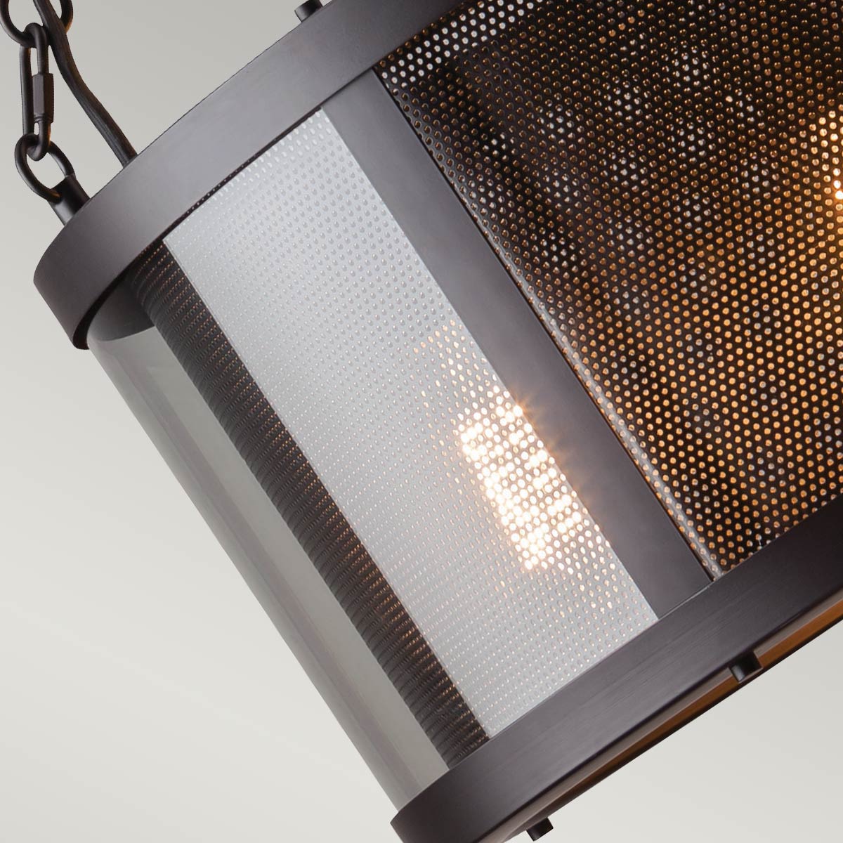 Vue rapprochée de l'abat-jour cylindrique montrant la grille perforée et le verre dépoli