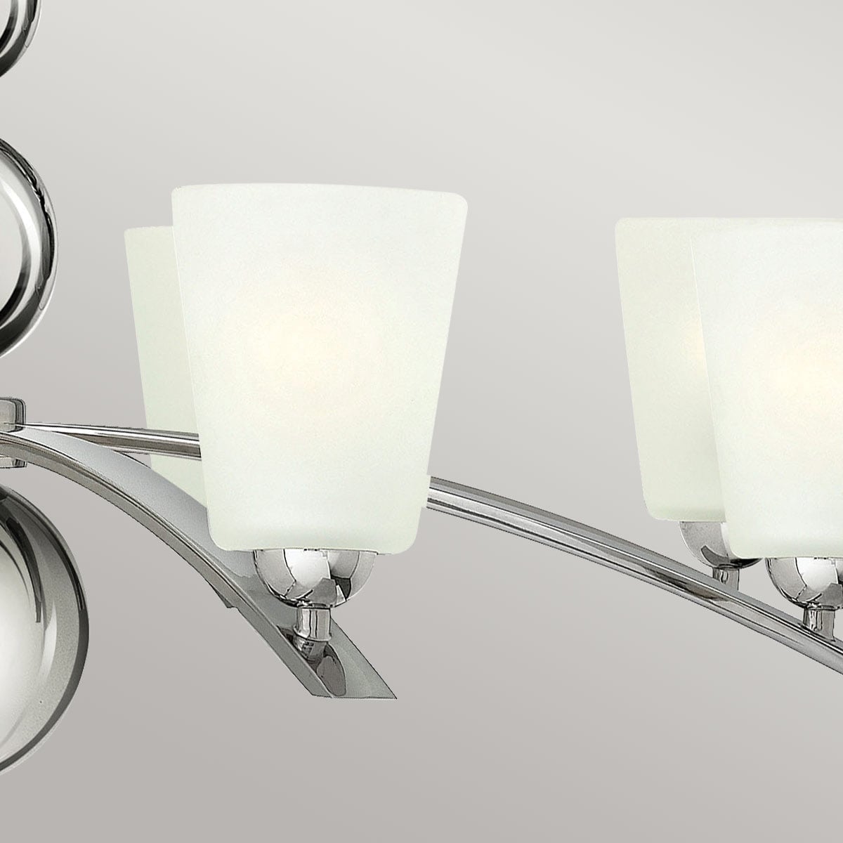 Détail des bras incurvés en métal brillant supportant les coupelles en verre blanc.