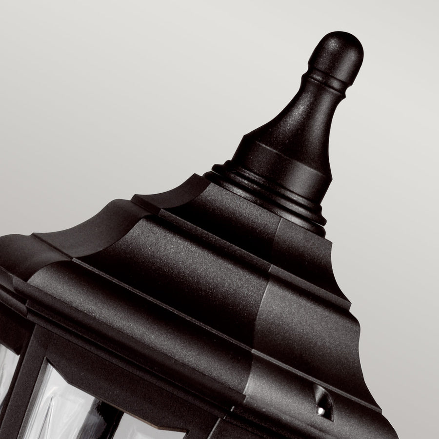 Gros plan sur le sommet noir ouvragé et la pointe décorative de la lanterne