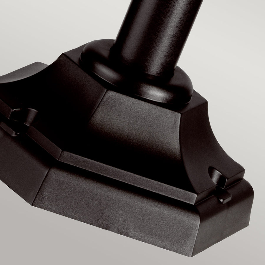 Gros plan sur la base octogonale noire et le pied cylindrique du lampadaire