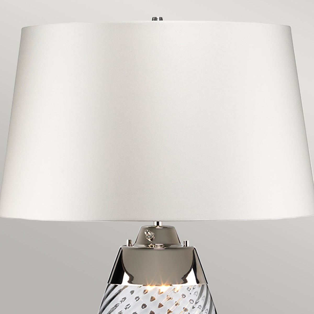 Gros plan sur l'abat-jour blanc et la bague chromée au sommet de la lampe