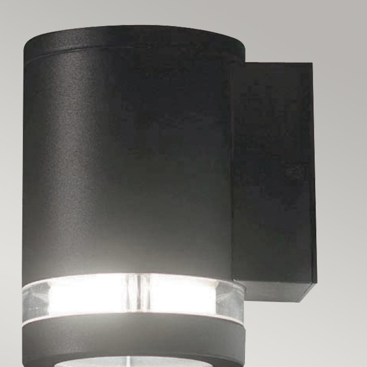 Gros plan de l'applique cylindrique noire, diffuseur annulaire lumineux sous le corps.