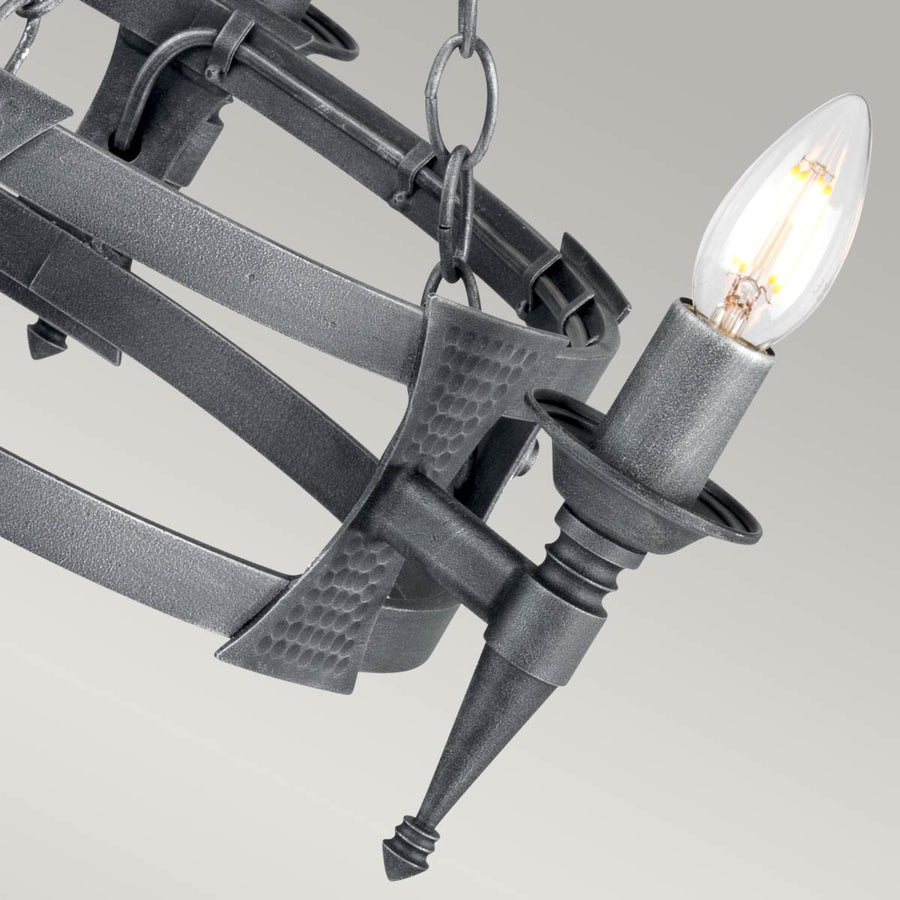 Détail d'un bras lumineux, plaque martelée et bougie avec ampoule transparente.
