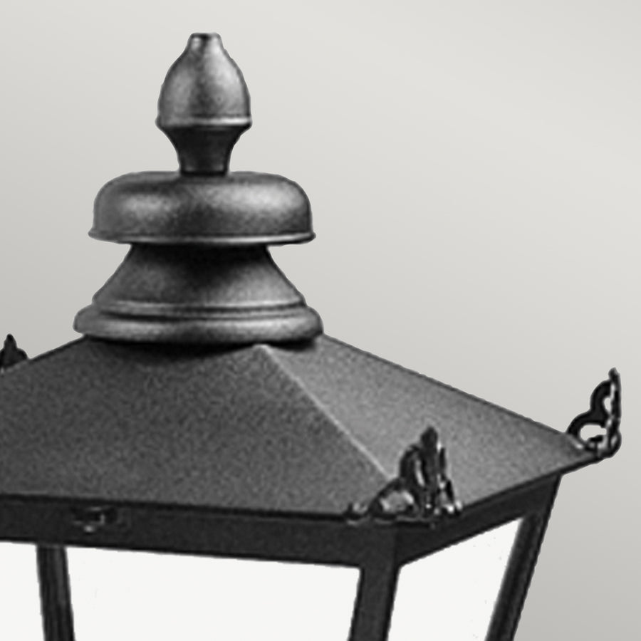 Détail du sommet : chapeau noir à quatre pans et finial ouvragé de la lanterne.