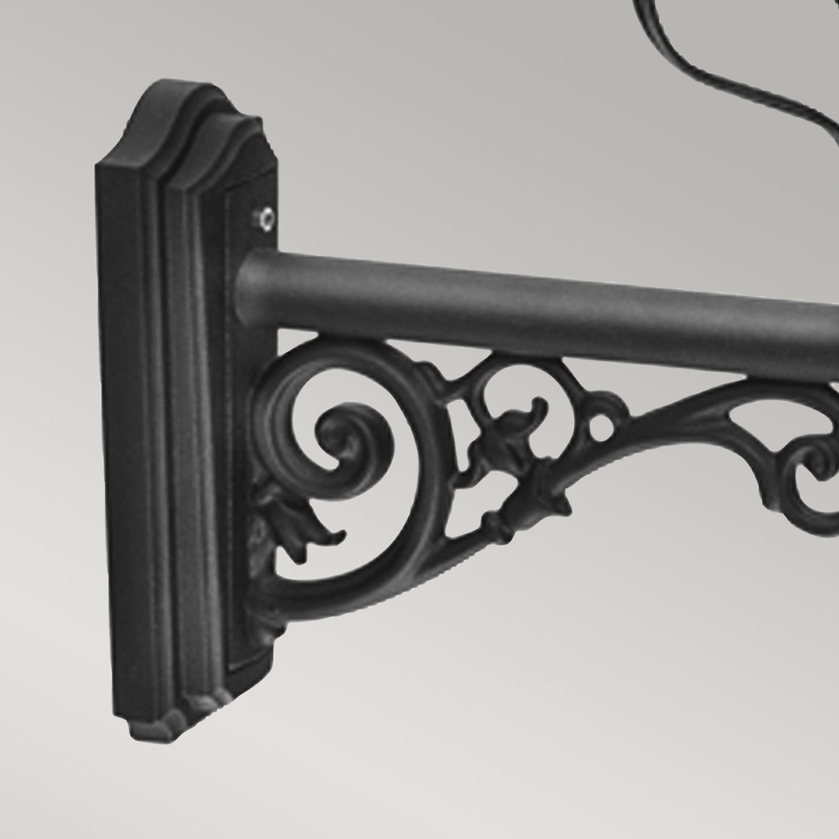 Détail de la platine murale et du bras orné de volutes ajourées, fixé au support.