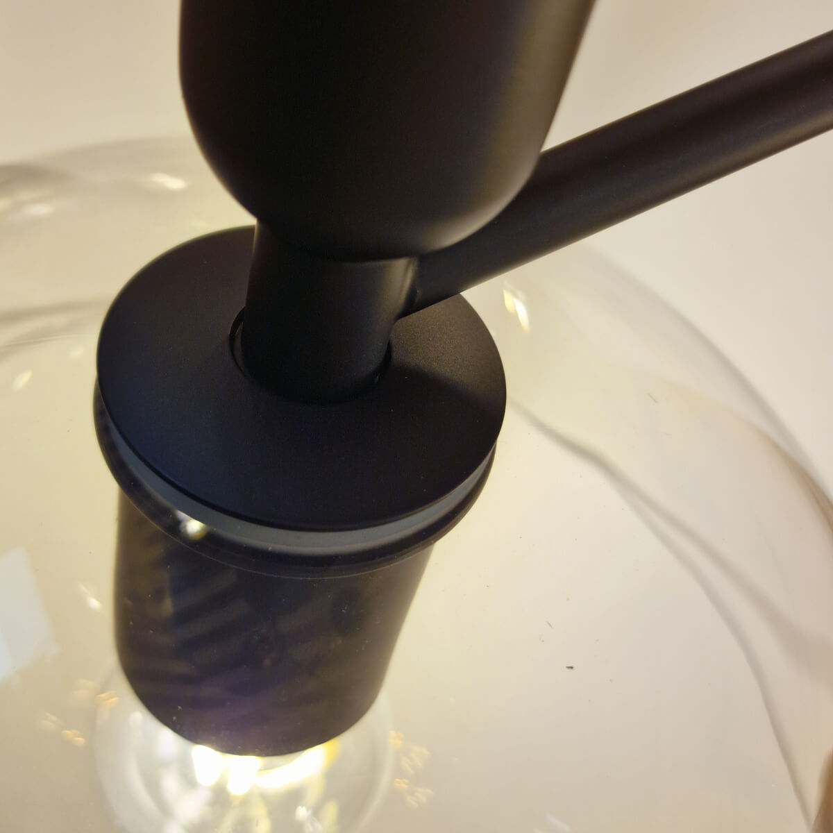 Détail du raccord entre le bras noir mat et la coupole en verre transparent