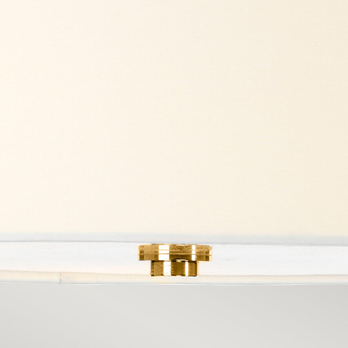 Détail de la petite fixation dorée sous l'abat-jour blanc du luminaire