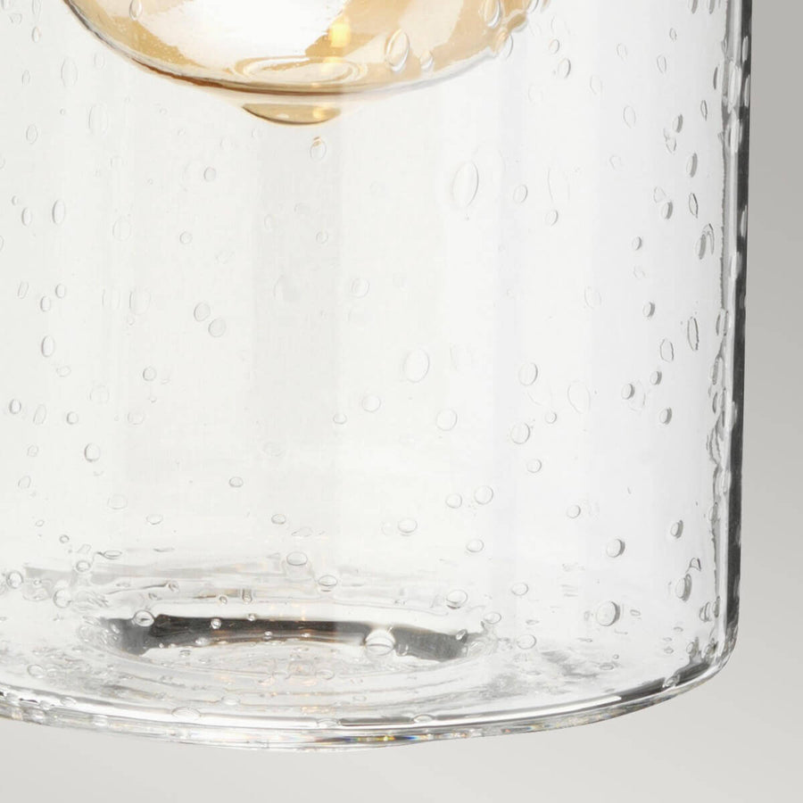 Détail du verre soufflé moucheté avec bulles d'air et reflets lumineux.