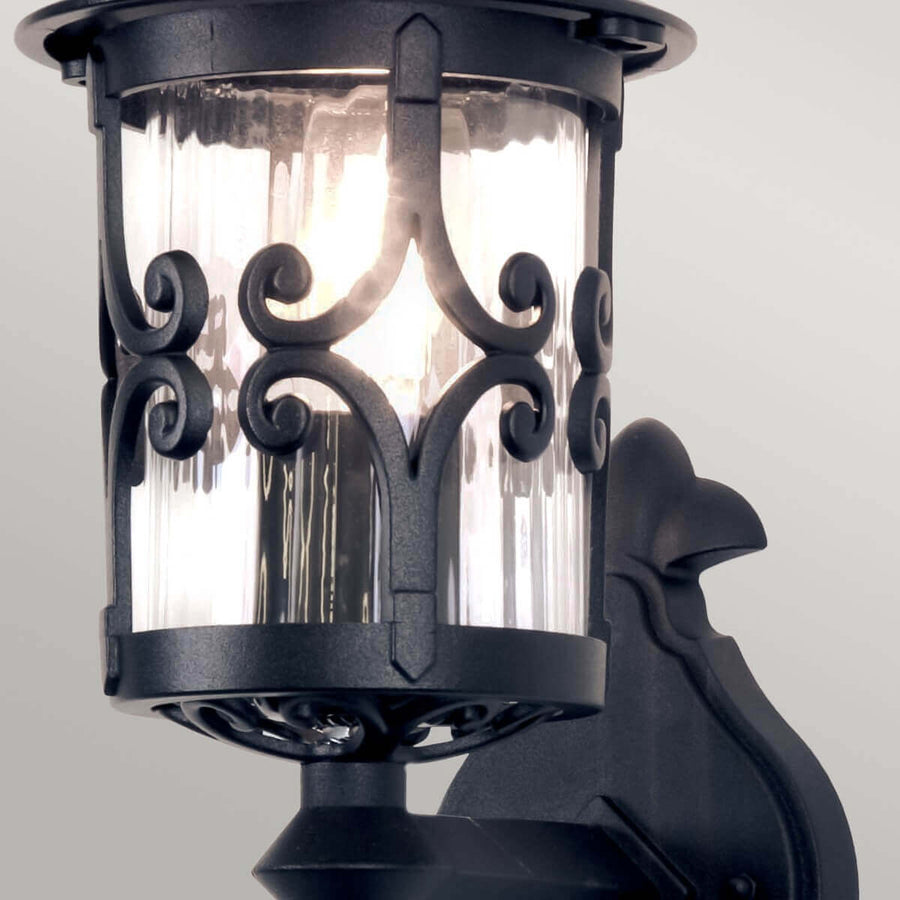 Vue rapprochée du cylindre de verre strié et des ferrures ornementales noires