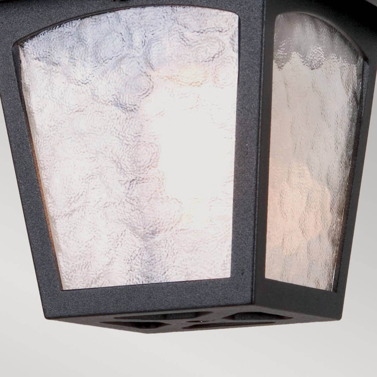 Gros plan du verre texturé et de la base ajourée du luminaire