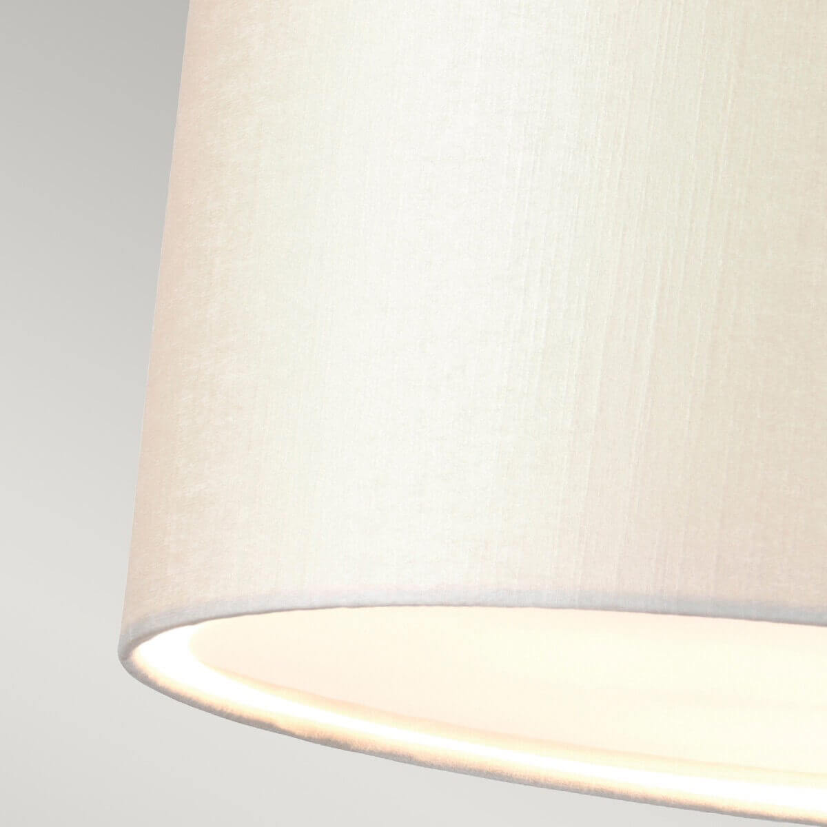 Détail de la texture tissu crème et bord inférieur éclairé de l'abat-jour