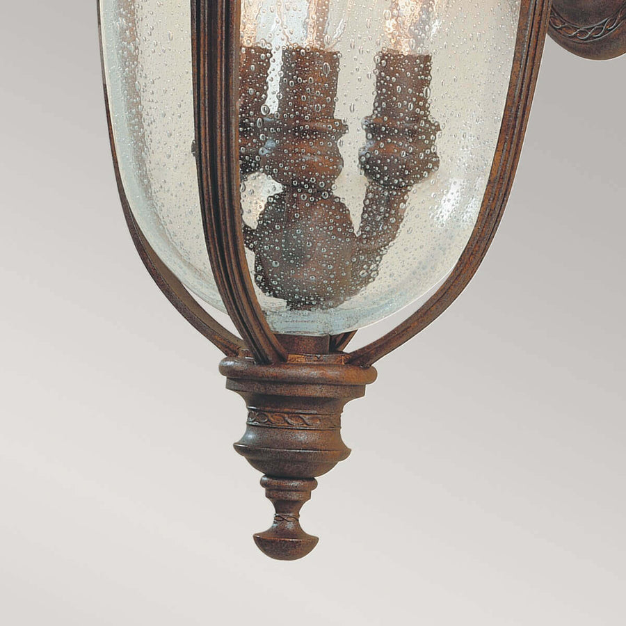 Gros plan sur le bas de la lanterne, verre bullé et finial bronze ouvragé suspendu.