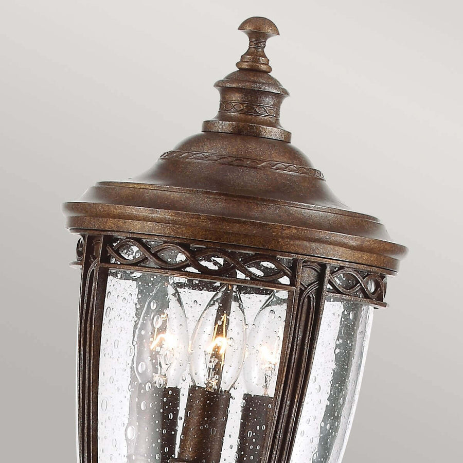 Détail du haut de la lanterne avec finial, verre moucheté et ampoules allumées.