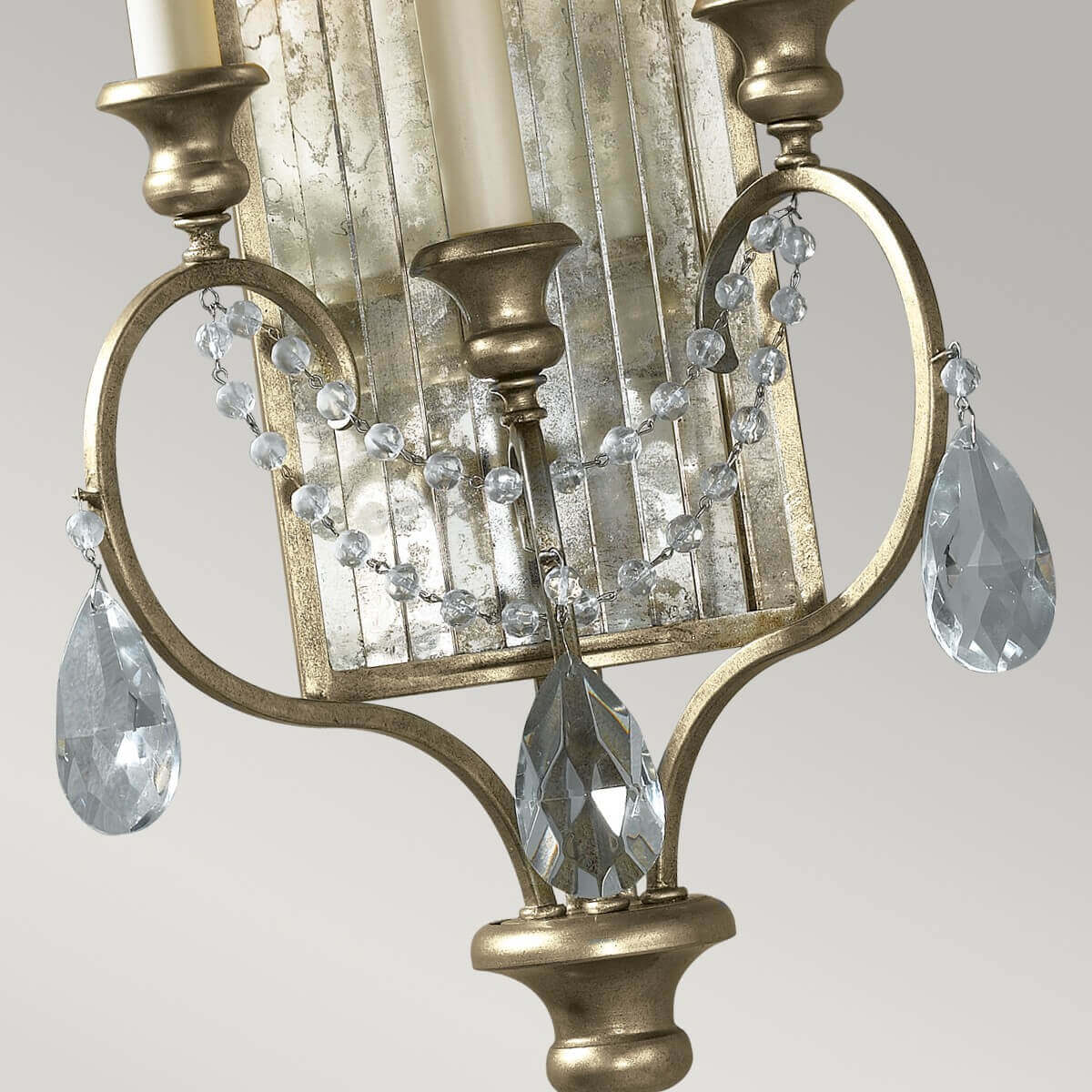 Détail des bras courbés dorés, chaînettes de perles et pampilles en cristal taillé
