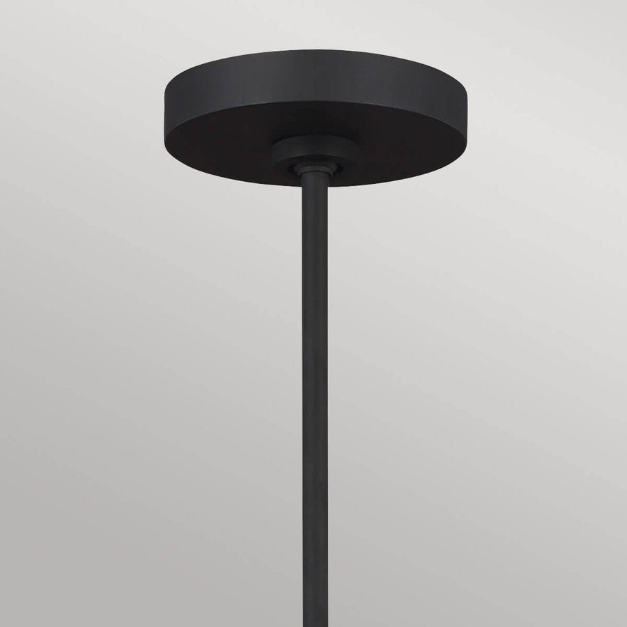 Détail de la rosace de plafond noire et de la tige de suspension verticale