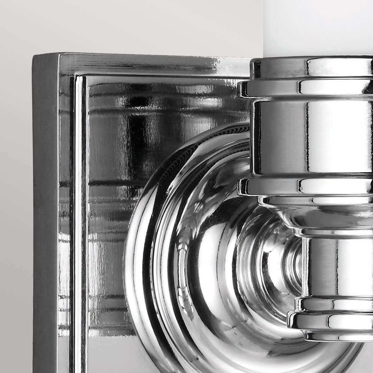 Détail de la platine murale carrée et de l'attache circulaire en chrome poli.