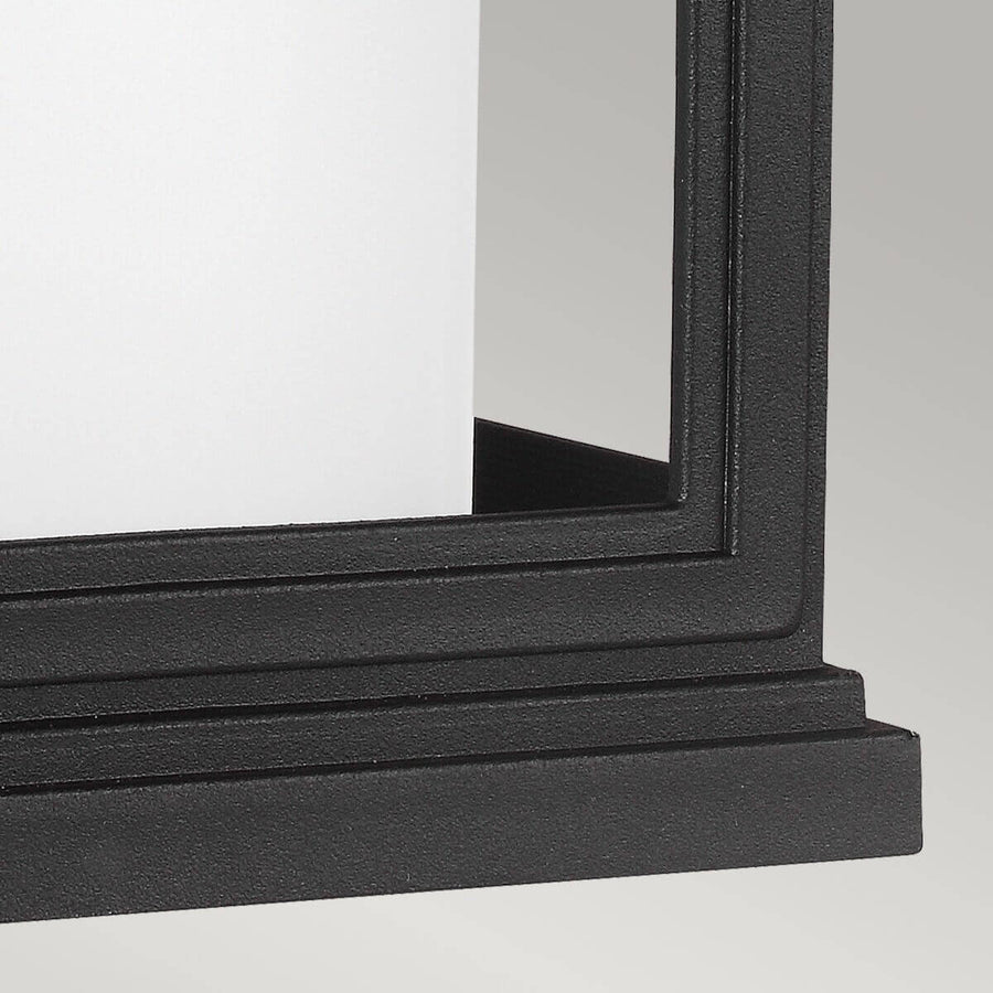 Détail du bas de l'applique avec moulure noire et panneau de verre dépoli.