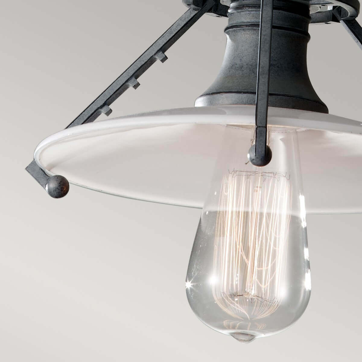 Gros plan sur l'abat-jour transparent et l'ampoule Edison allumée aux filaments visibles.