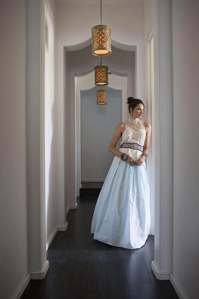 Couloir blanc éclairé par trois suspensions identiques, femme en robe longue