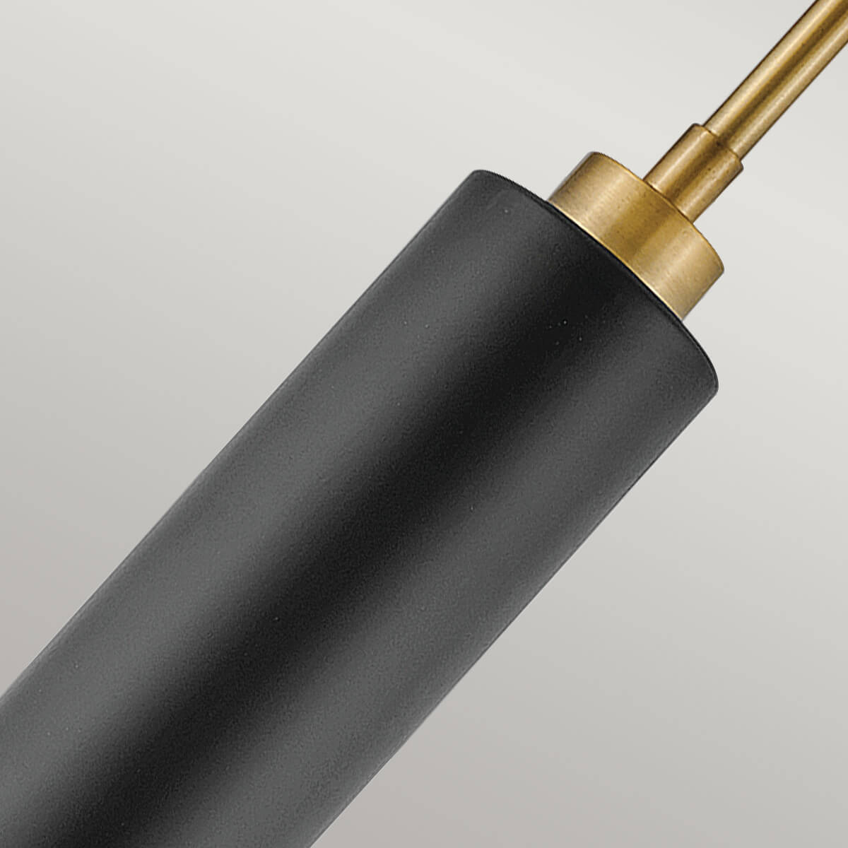 Détail du raccord en laiton brossé sur le corps cylindrique noir mat.