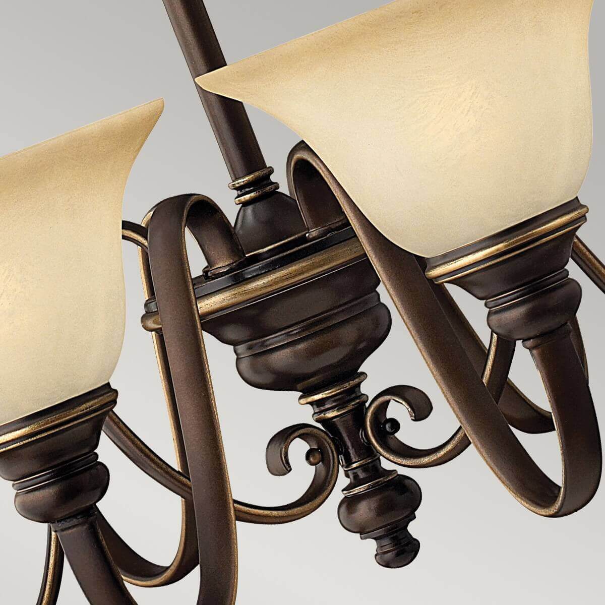 Vue rapprochée des bras courbes, volutes décoratives et base centrale du luminaire