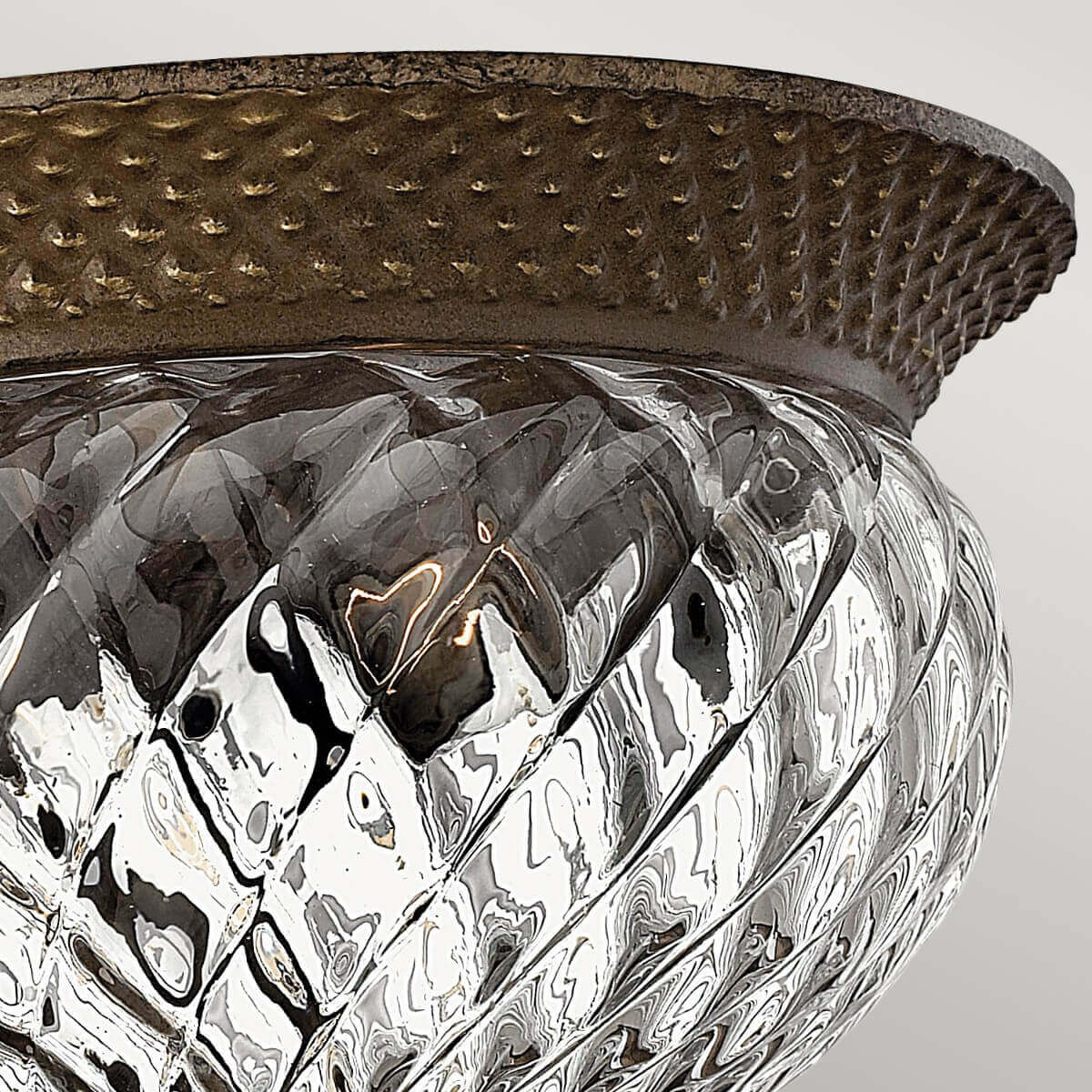 Détail du bord en métal bronze martelé surmontant le verre mouluré