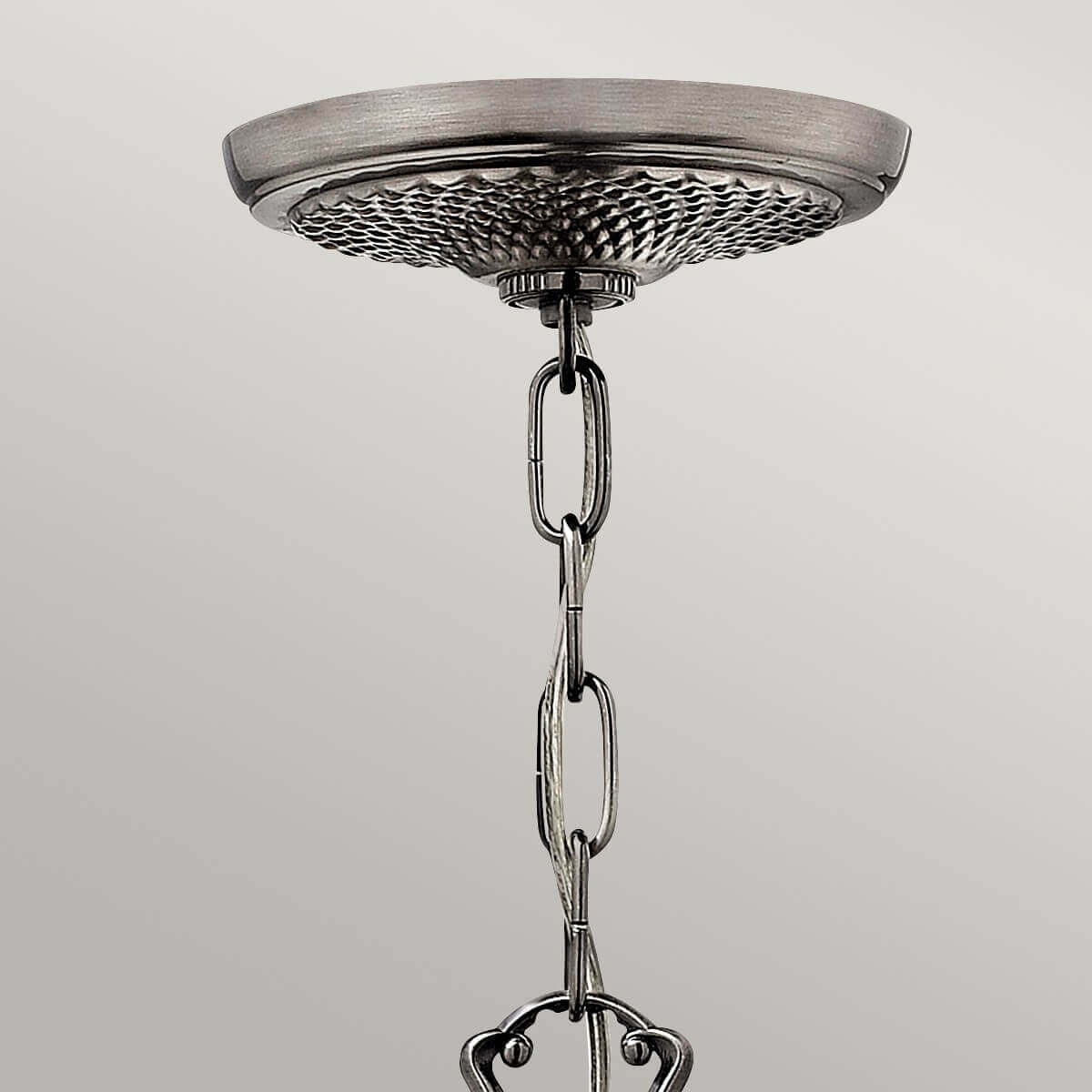 Gros plan sur la rosace de plafond nickel et la chaîne de suspension.