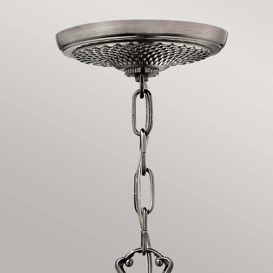 Gros plan sur la rosace de plafond nickel et la chaîne de suspension.