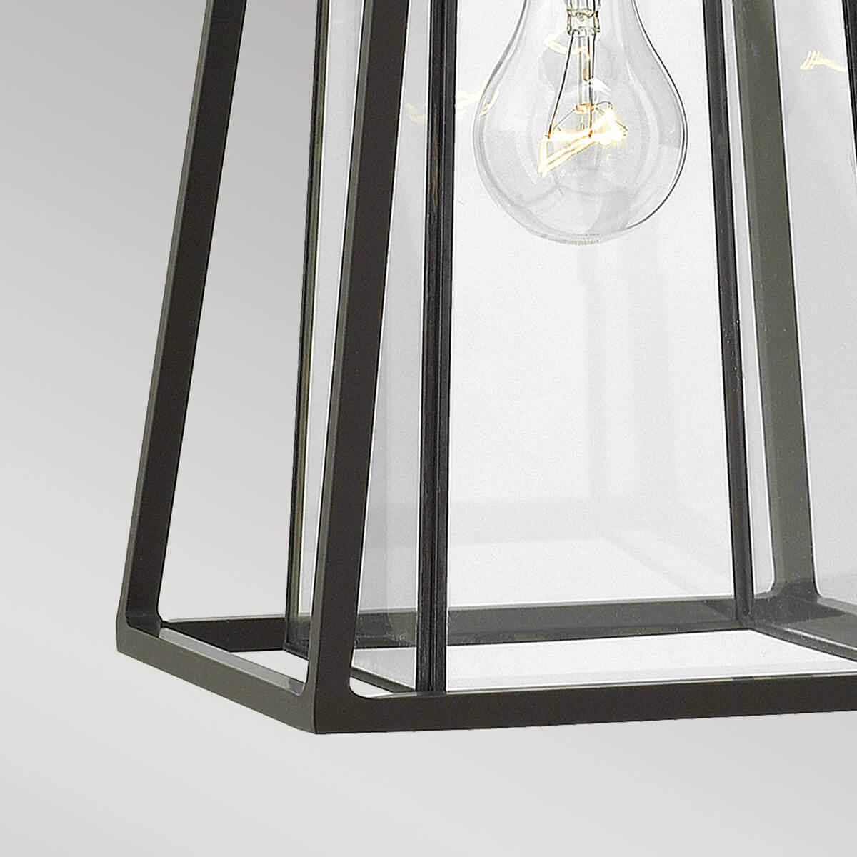 Gros plan sur le bas du cadre métallique et les panneaux de verre transparent.