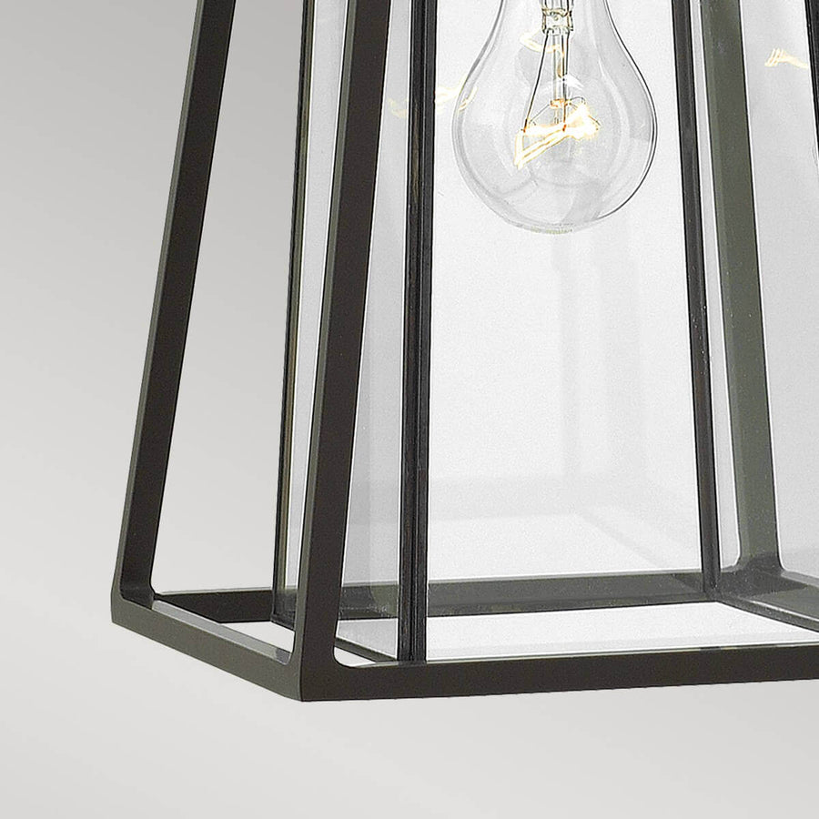 Gros plan sur le bas du cadre métallique et les panneaux de verre transparent.