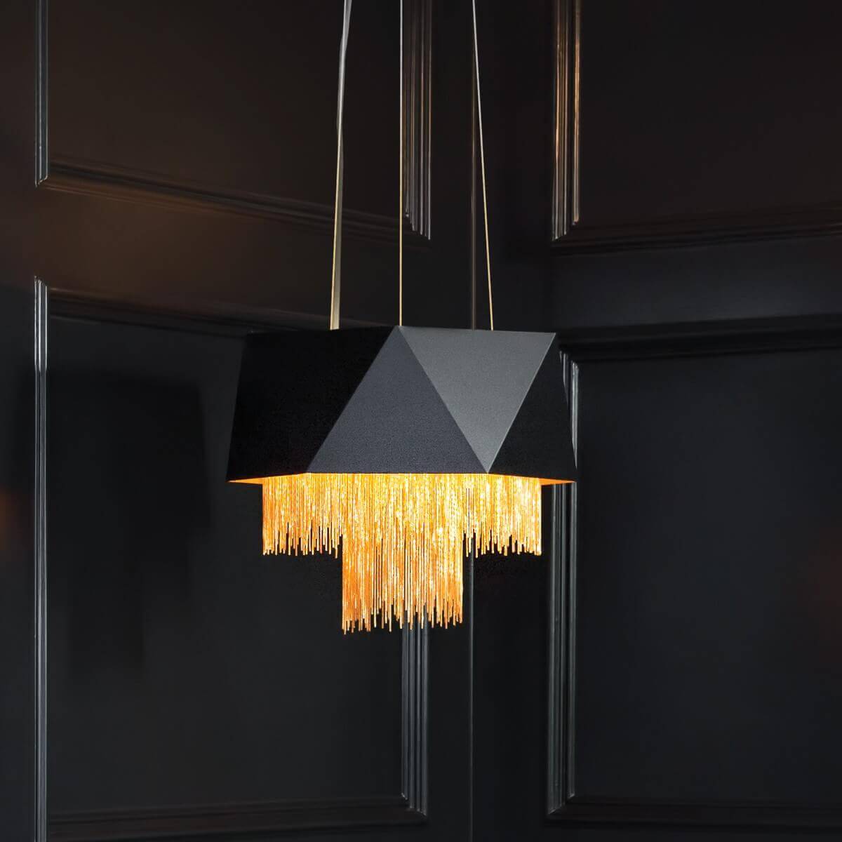 Suspension allumée dans un intérieur sombre, franges dorées illuminées