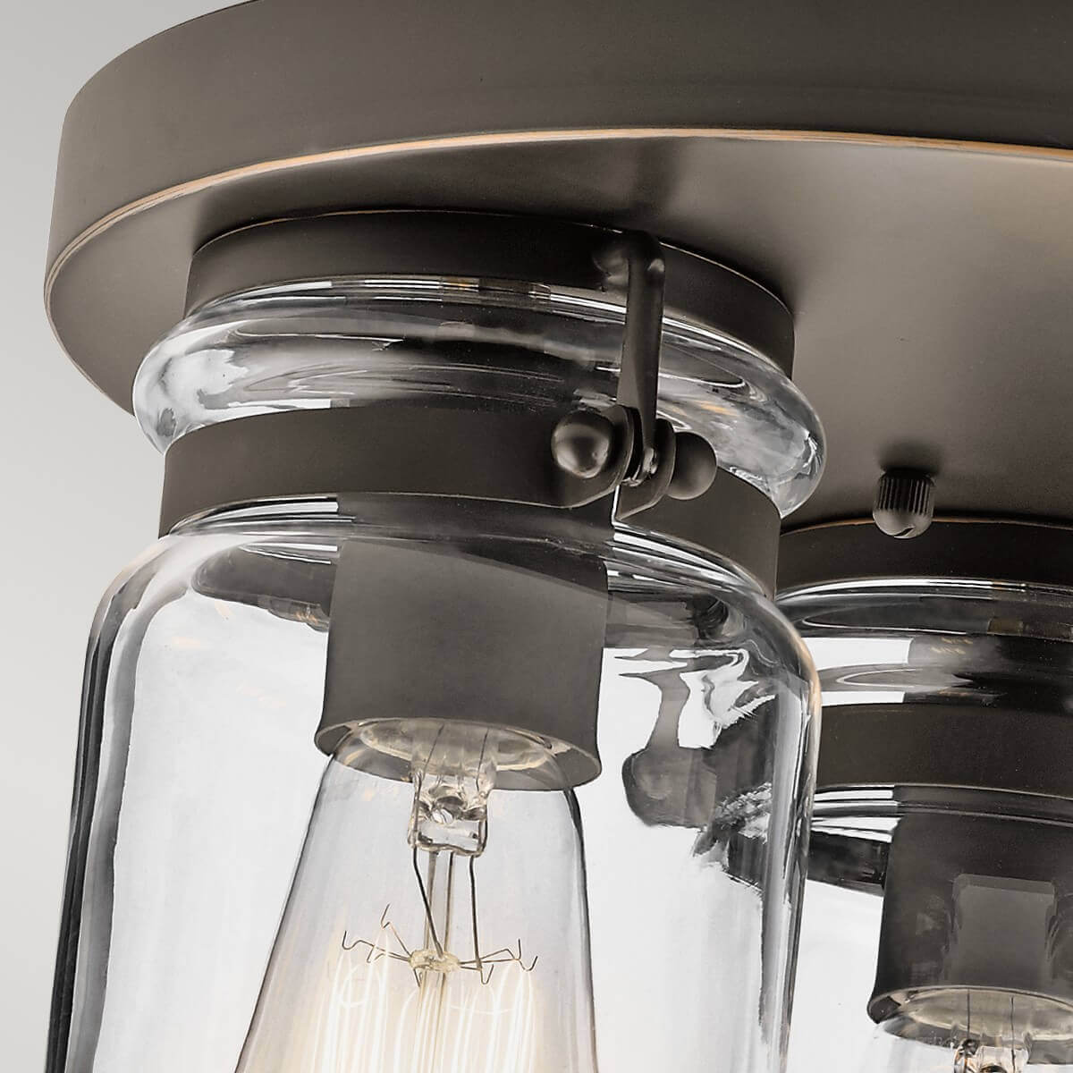 Gros plan sur la fixation du verre et la vis moletée maintenant l'abat-jour au plafonnier