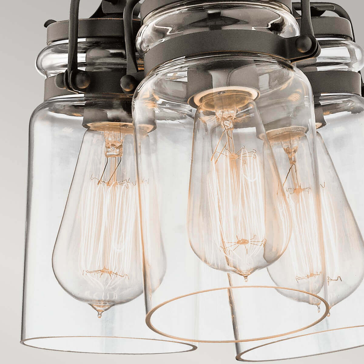 Gros plan sur les ampoules à filament doré placées dans les abat-jour en verre transparent.