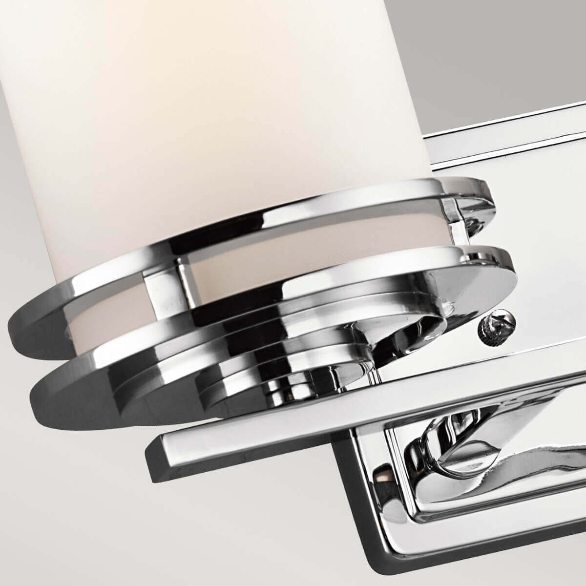 Gros plan sur la bague chromée maintenant le diffuseur cylindrique en verre opalin.