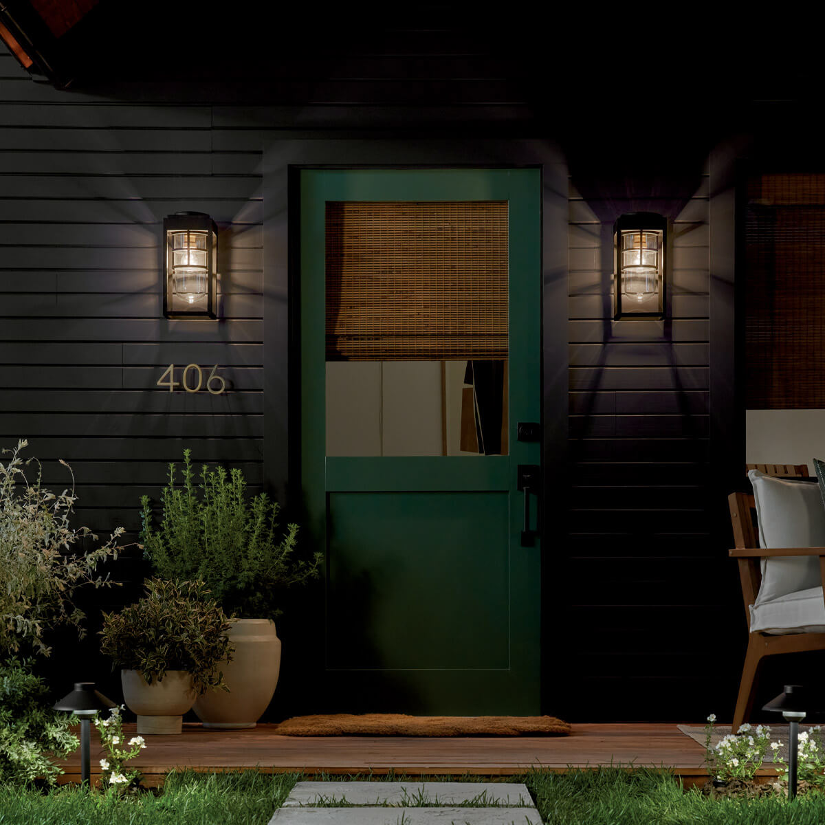 Mise en ambiance nocturne, deux appliques encadrant une porte verte d'entrée