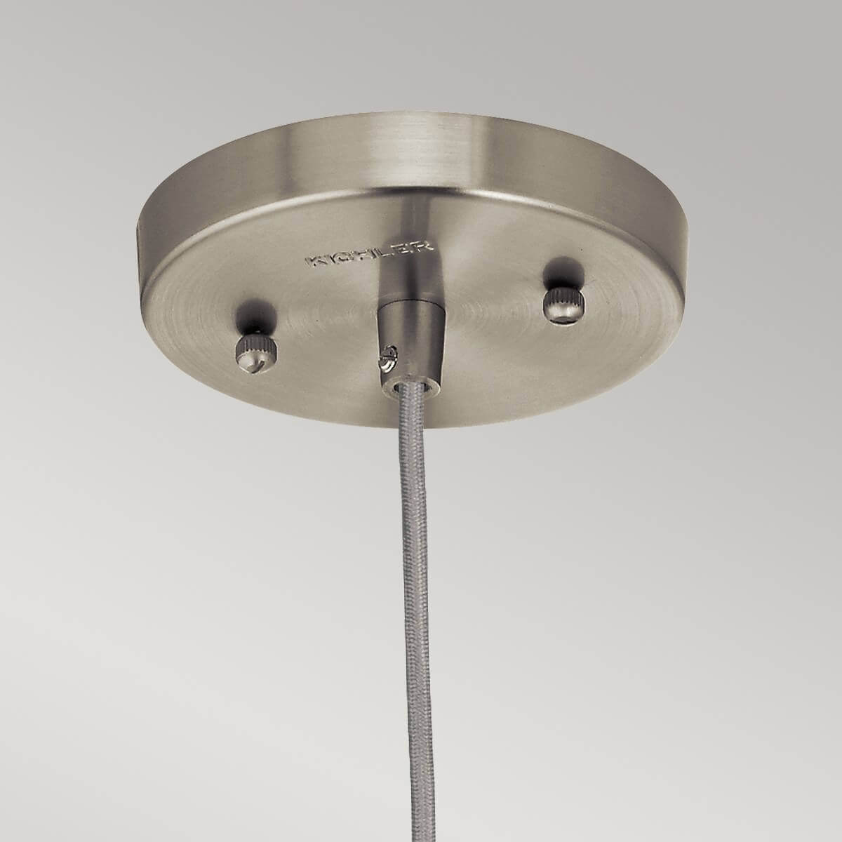 Détail du pavillon rond en nickel brossé fixé au câble tressé gris