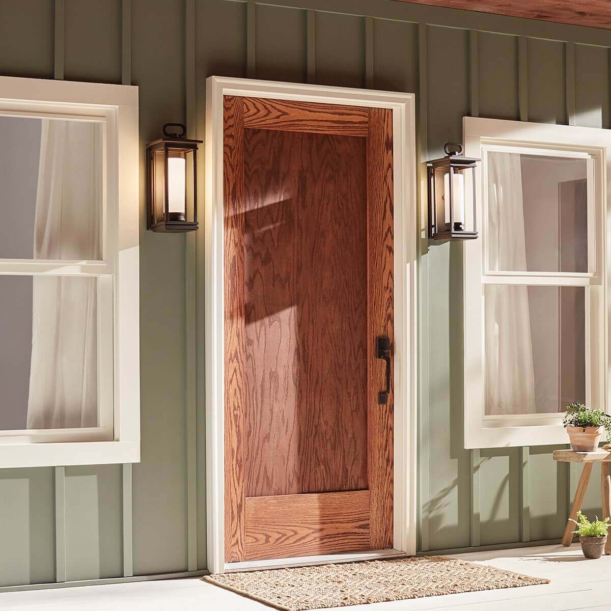 Vue de face sur une porte en bois, deux appliques encadrant l'entrée