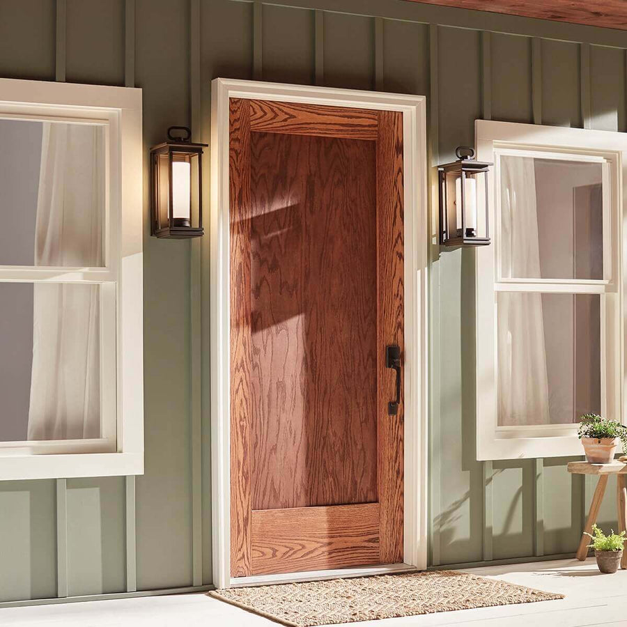 Vue de face sur une porte en bois, deux appliques encadrant l'entrée