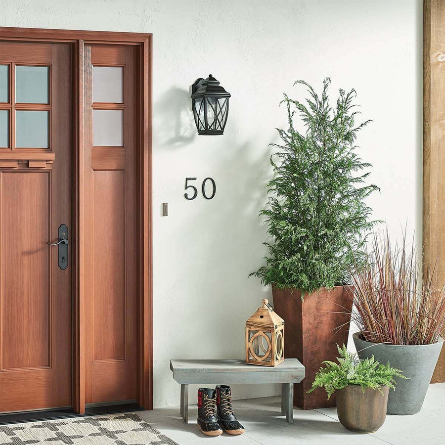 Mise en situation de jour sur une façade blanche, près d'une porte en bois