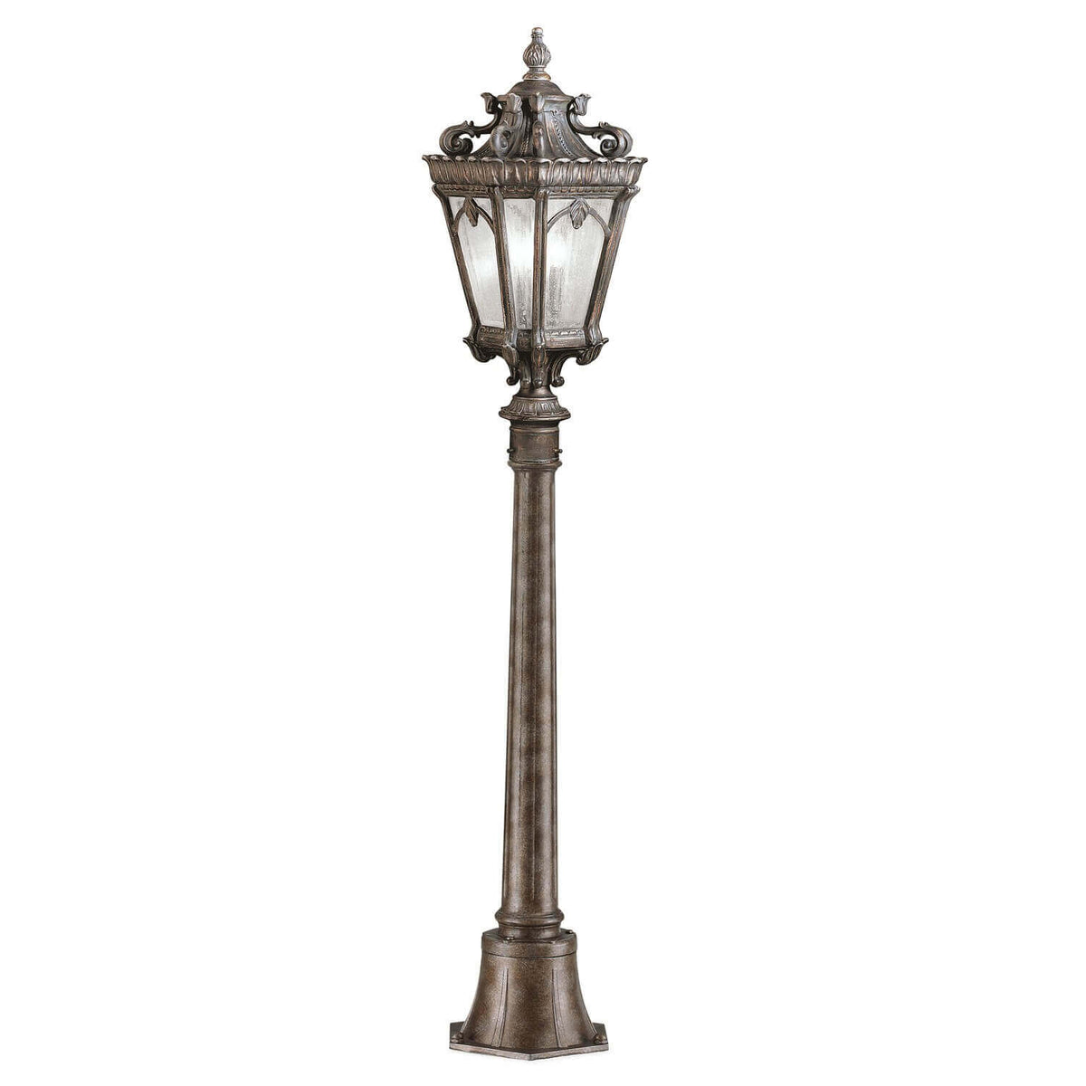 Lampadaire extérieur complet vu de face, lanterne en verre et long fût métallique patiné.