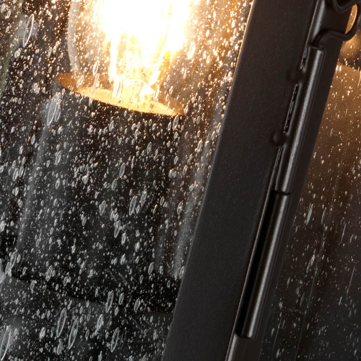 Zoom sur l'ampoule allumée derrière le verre constellé de gouttes de pluie