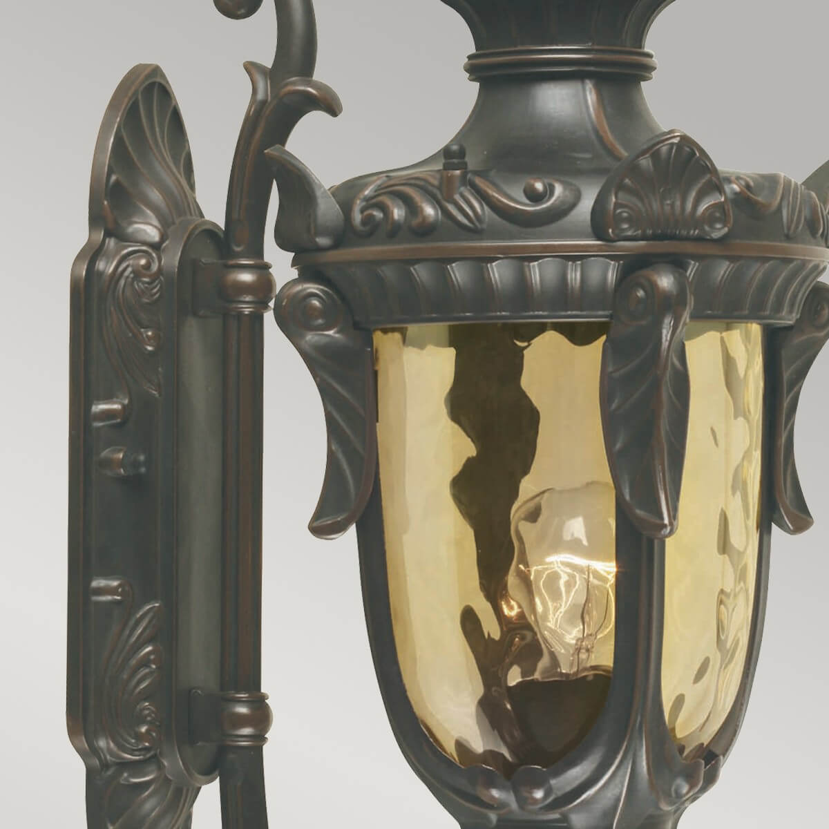 Détail du verre ambré martelé et de la platine murale ornée de volutes