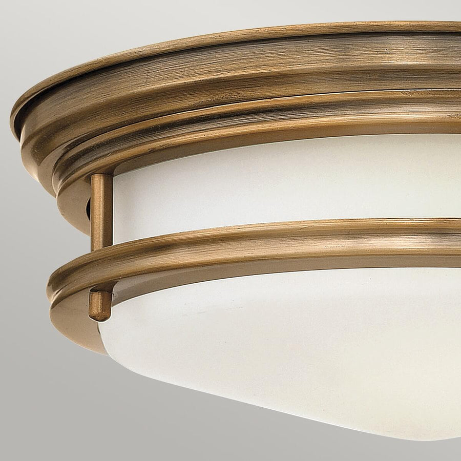 Gros plan sur le cerclage bronze brossé et la fixation par tige verticale du verre