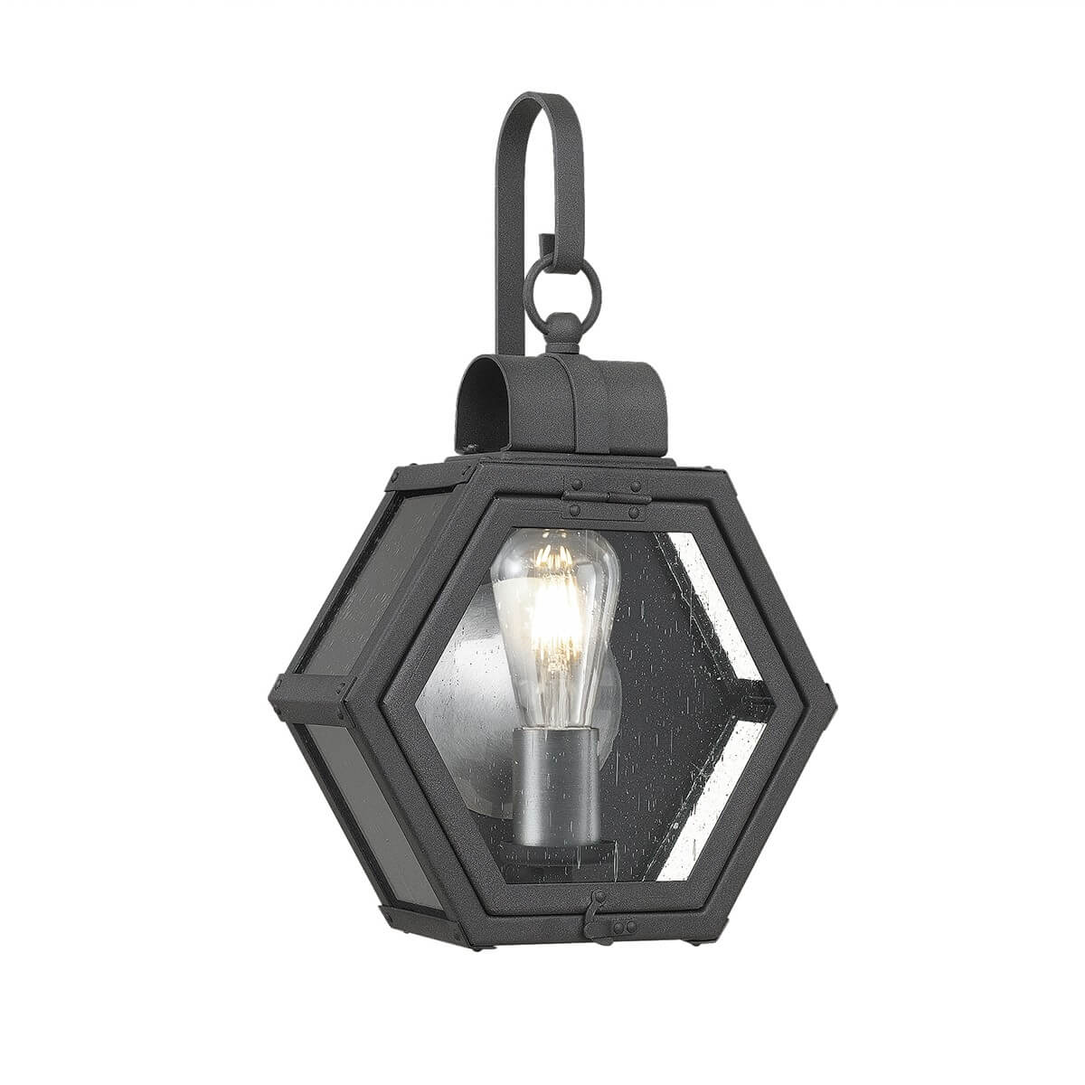 Luminaire hexagonal noir de face, ampoule allumée visible derrière le verre strié