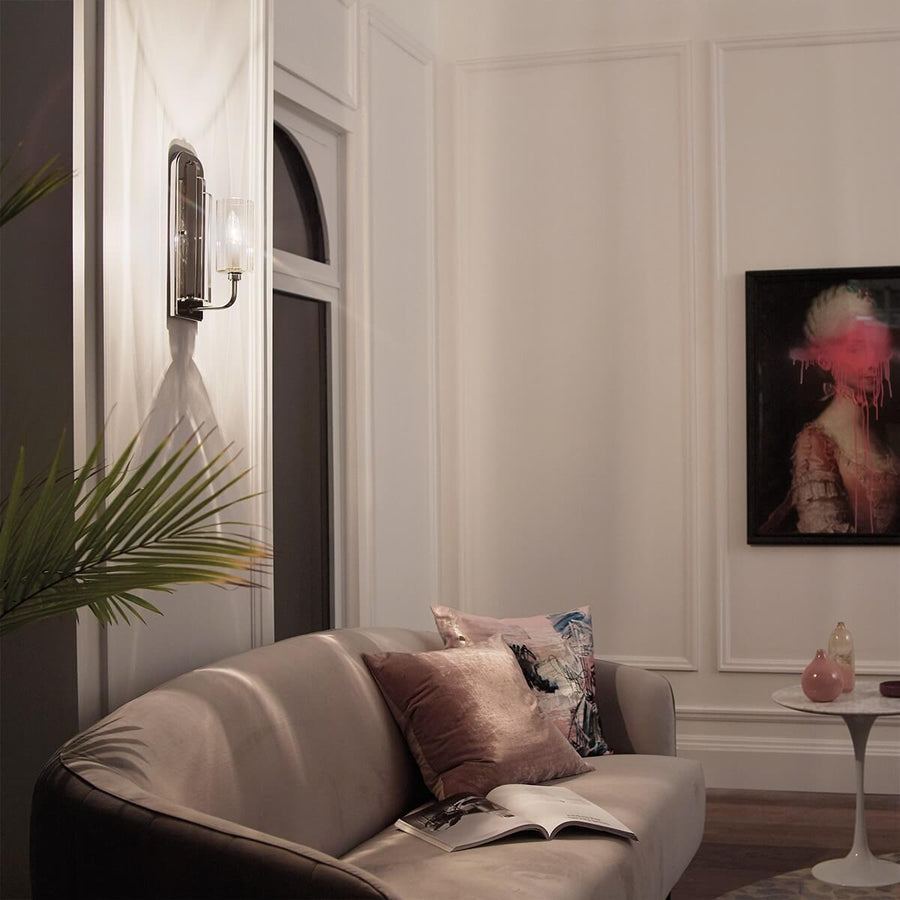 Vue de nuit : la même applique murale éclaire chaleureusement le salon et le canapé.